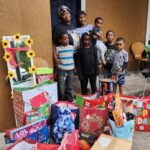 Founder and a group of children surrounded by christmas gifts