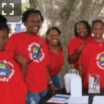 A group of people smiling with Better Together Community Event t-shirts