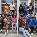 Founder and a group of teens sitting on stairs eating sweets and smiling